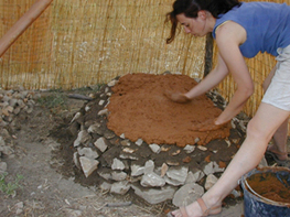 Construction expérimentale d’un four : les premières couches de terre à bâtir sont étalées au-dessus de la fondation en pierre.