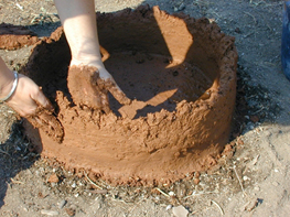 Construction expérimentale d’un silo : lissage des colombins en terre à bâtir.